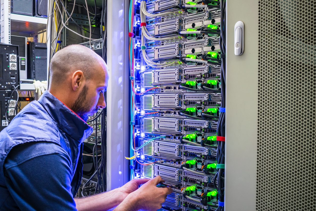 A man works with telecommunications. The technician switches the Internet cable of the powerful routers. A specialist connects the wires in the server room of the data center. A man works with telecommunications. The technician switches the Internet cable of the powerful routers. A specialist connects the wires in the server room of the data center.