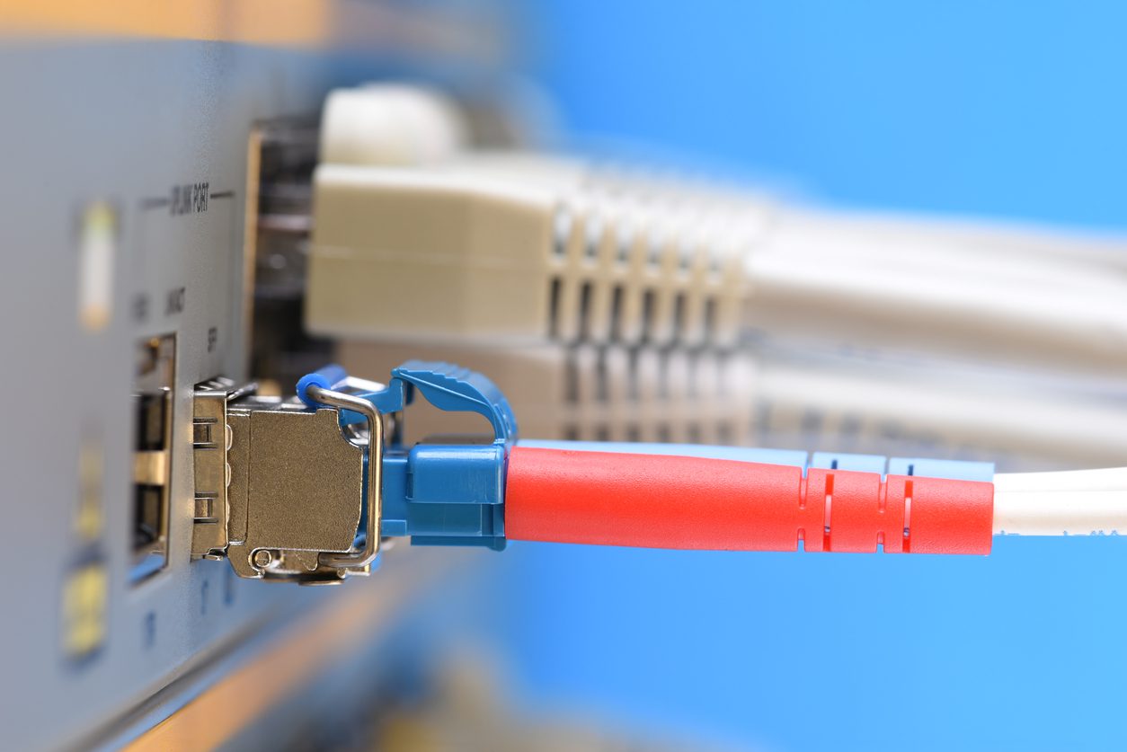 Optical fiber patch cord and network cables connected to switch in datacenter, closeup